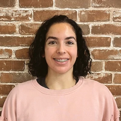 Gabriela Lopez smiling in front of a brick wall.