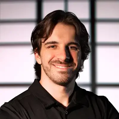 Professional headshot of a person with medium-length dark hair wearing a black collared shirt